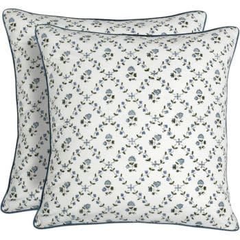 Two square pillows with a white background and a pattern of small blue flowers arranged in a diagonal grid. The edges of the pillows are trimmed with dark piping.