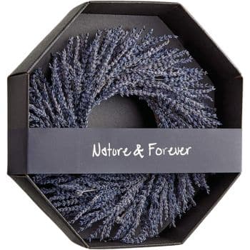 A neatly arranged wreath of dried lavender sits inside a hexagonal black box. The box's band reads "Nature & Forever" in white lettering. The lavender forms a spiral pattern within the box.