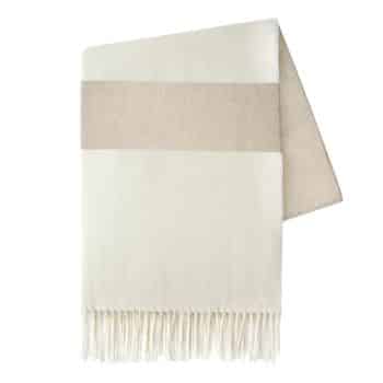 A soft, fringed throw blanket with a wide beige stripe across the middle, surrounded by a light cream color. The blanket is neatly folded, showcasing its elegant and minimalist design.