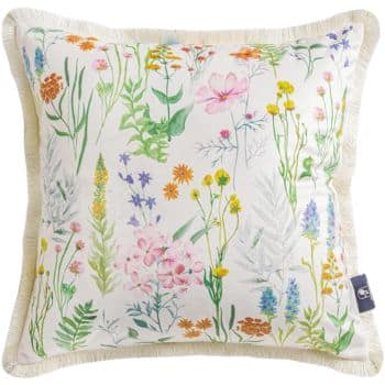 A square decorative pillow with a colorful floral pattern, featuring various flowers and leaves in pink, yellow, orange, blue, and green hues. The pillow has fringed edges and a soft, white background.