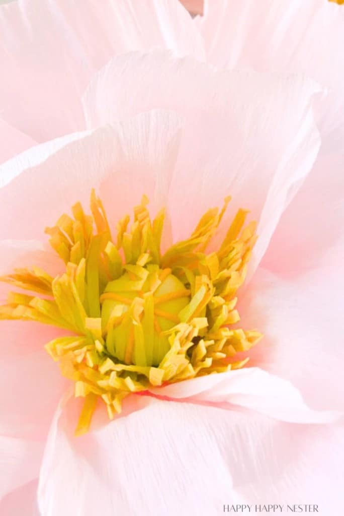 Close-up of a pink crepe paper flower with a bright yellow center, showcasing delicate, layered petals and intricate textures—perfect for adding to your DIY flower garland.