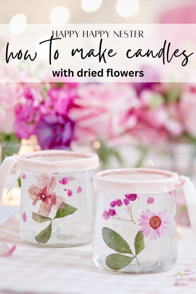 Two glass candles decorated with dried flowers and leaves are placed on a table. The background is softly blurred with pink flowers. Text at the top reads: "Happy Happy Nester: how to make candles with dried flowers.