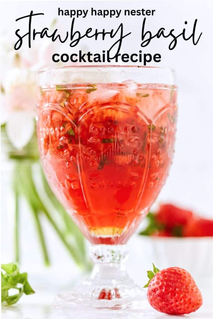 A vibrant strawberry basil cocktail in a decorative glass, surrounded by fresh strawberries and basil. Handwritten text above the glass reads, "Happy Happy Nester's Signature Recipe: The Ultimate Strawberry Basil Cocktail.