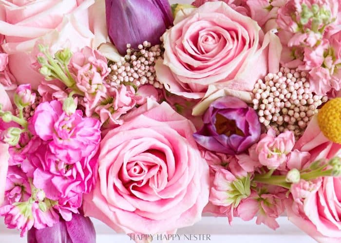 A vibrant bouquet featuring pink roses, purple tulips, and assorted pink flowers creates a lush, colorful arrangement perfect for Valentine's table centerpieces.