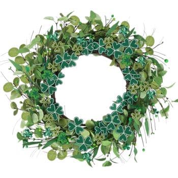 A decorative wreath featuring green shamrocks and leafy plants arranged in a circular shape. The shamrocks are adorned with gold accents, creating a festive and natural look. There is a blank space in the center of the wreath.