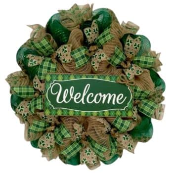 A decorative wreath with a "Welcome" sign in the center. The wreath features green and gold ribbons with shamrock patterns, likely for St. Patrick's Day or a similar festive occasion.