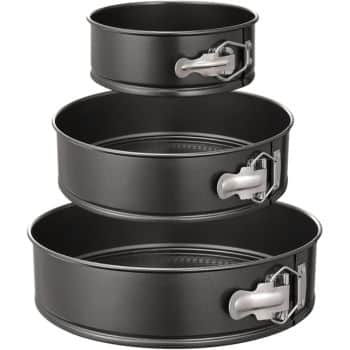 Three black metal springform cake pans with silver latches are stacked vertically. Each pan, ideal for crafting the best spring cakes, is a different size, arranged from smallest to largest to showcase their nesting capability.