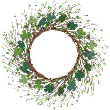 A decorative wreath made of intertwined twigs, adorned with green shamrocks and small green berries, arranged in a circular pattern. The center of the wreath is empty, creating an open space.