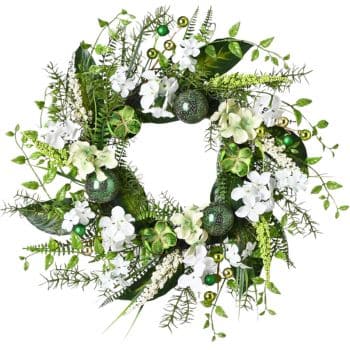 A decorative wreath with green leaves, white flowers, and small green baubles and accents. The arrangement is circular and vibrant, featuring various shades of green and white, giving a fresh and festive appearance.