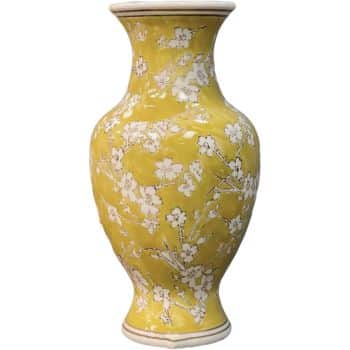 A yellow ceramic vase with a glossy finish, adorned with intricate white floral patterns. The vase has a narrow neck and a wide body, showcasing elegant, blooming branches.