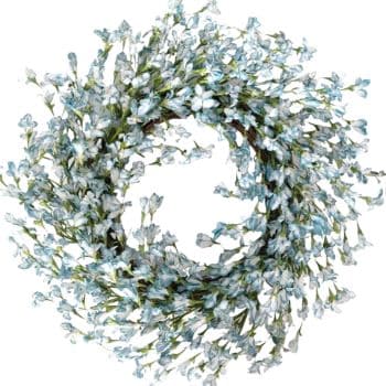 A circular wreath made of delicate, small blue and white flowers with green stems and leaves, arranged densely on a white background.