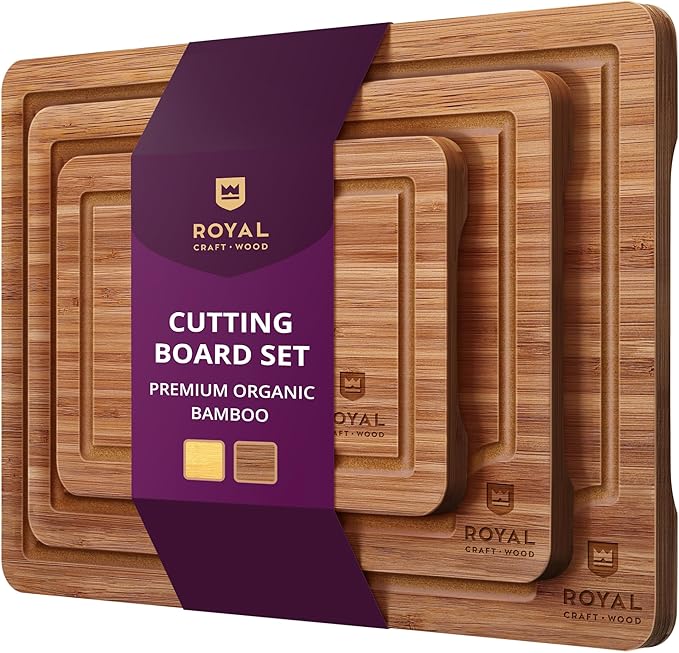 A set of four rectangular bamboo cutting boards of varying sizes, perfect for learning how to make a tender juicy steak, stacked together and wrapped with a purple and gold label reading “Royal Craft Wood Cutting Board Set – Premium Organic Bamboo.”.