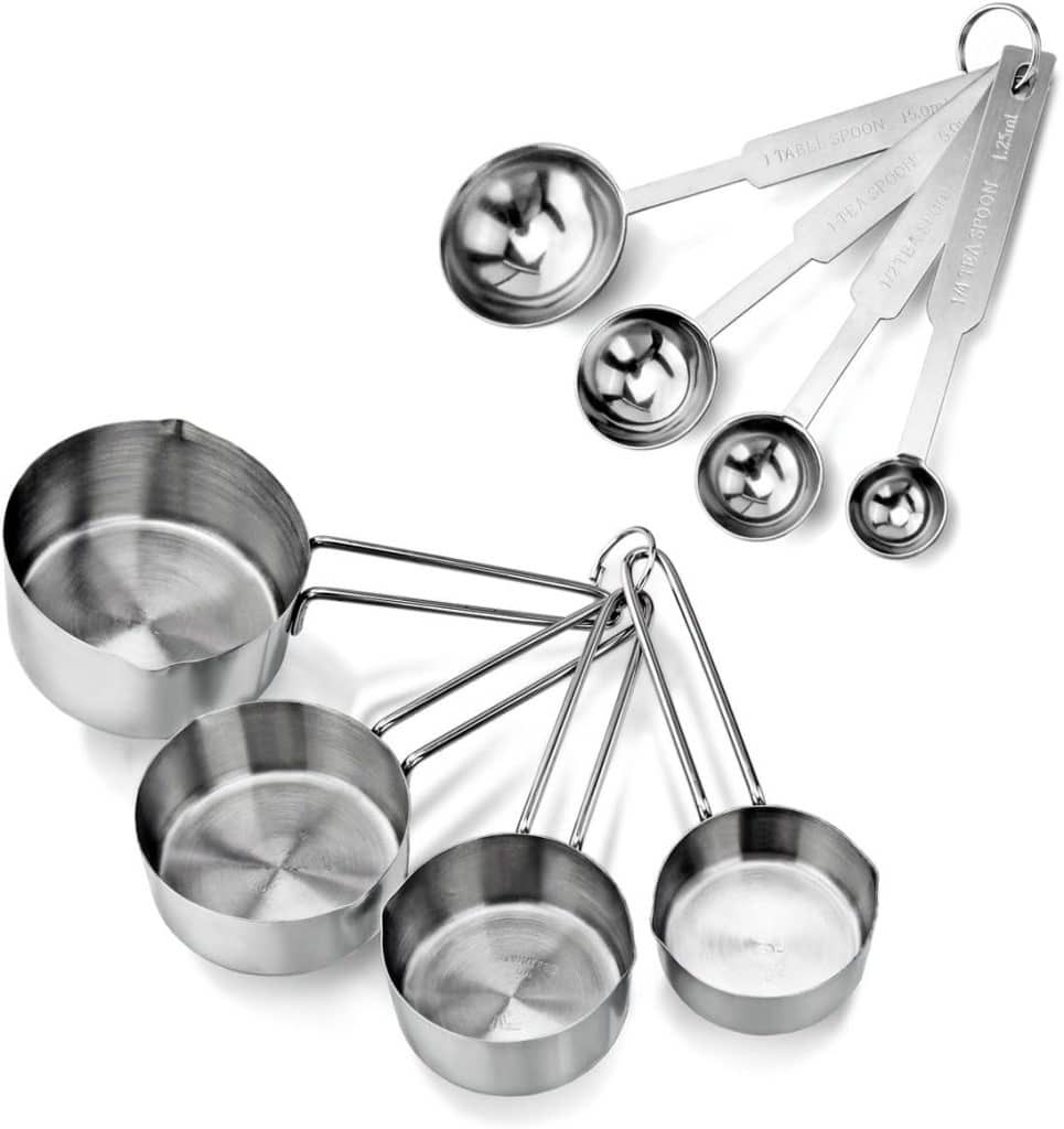 A set of four stainless steel measuring cups and five spoons, all nested together on a white background—essential tools whether you’re baking or learning how to make a tender juicy steak. Each set is attached by sturdy metal rings for easy storage.