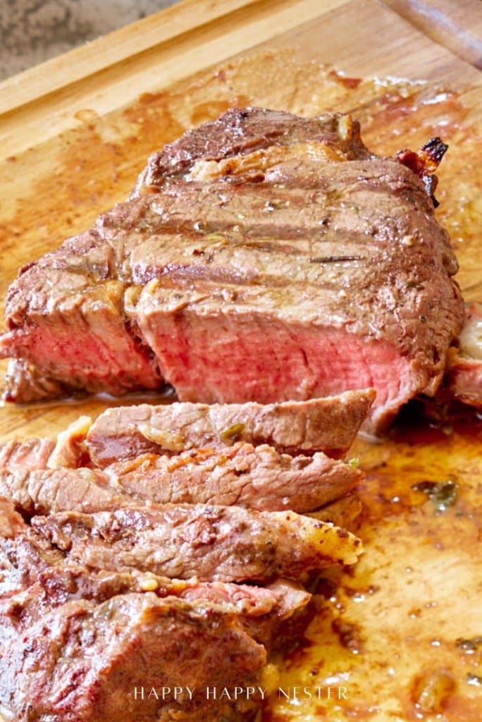 A juicy, medium-rare steak—sliced on a wooden cutting board with a visible pink center and juices pooling around the meat.
