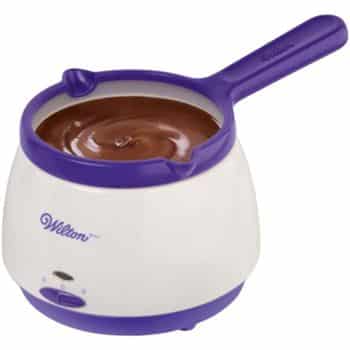 A Wilton electric chocolate melting pot with a white base, purple accents, and a handle, filled with smooth melted chocolate—perfect for making my favorite chocolate recipes.