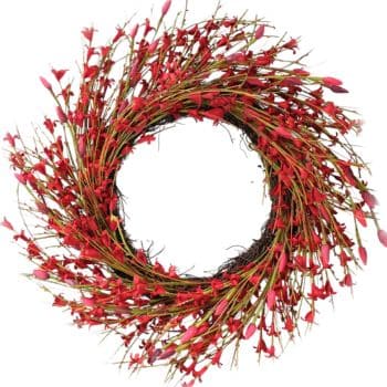 A circular wreath made of intertwined branches adorned with numerous small red and pink artificial flowers, arranged densely around the ring with a white background in the center.