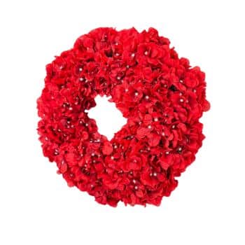 A circular wreath made of bright red artificial flowers with tiny white accents, arranged densely to form a decorative ring. The background is plain white.