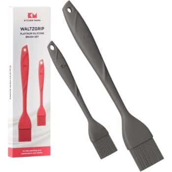 Two gray silicone basting brushes with textured handles are shown next to their packaging, perfect for preparing my favorite chocolate recipes. The box displays an image of the brushes and branding for Kitchen Mama’s WaltzGrip Platinum Silicone Brush Set.