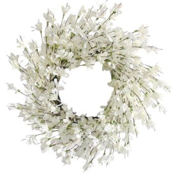 A round wreath made of delicate white artificial flowers on thin green stems, arranged densely to create a full, textured appearance against a white background.