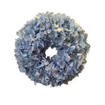 A circular wreath made of light blue artificial hydrangea flowers, arranged densely to form a full, textured ring.