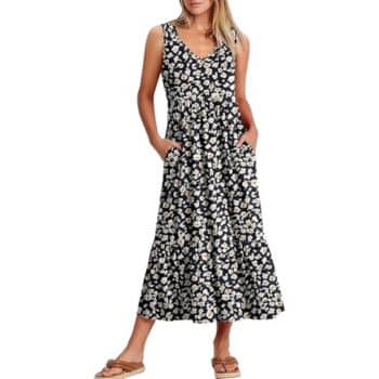 A woman wearing a sleeveless, V-neck, black maxi dress with a white floral pattern and side pockets, paired with tan flat sandals.