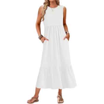 Woman wearing a sleeveless, ankle-length white dress with a fitted bodice and flared skirt, accessorized with bracelets, sandals, and wavy hair styled down.