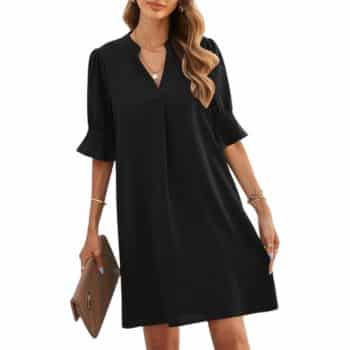 Woman wearing a loose-fitting black dress with elbow-length ruffled sleeves, holding a brown clutch. She has long, wavy hair and is accessorized with bracelets and necklaces.