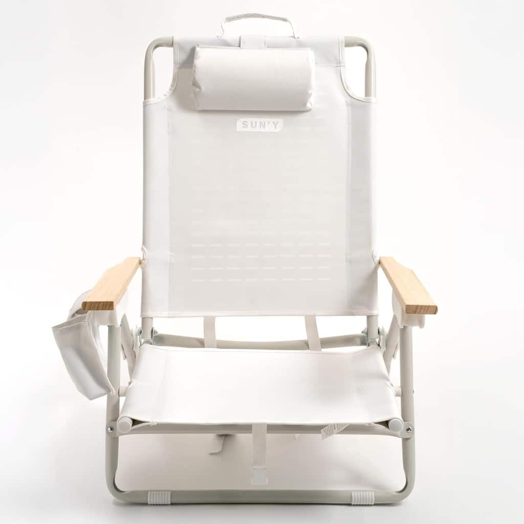 A white beach chair with light wood armrests, a headrest pillow, a built-in side pouch, and a minimalist design pairs perfectly with outdoor tables and chairs, set against a plain white background.