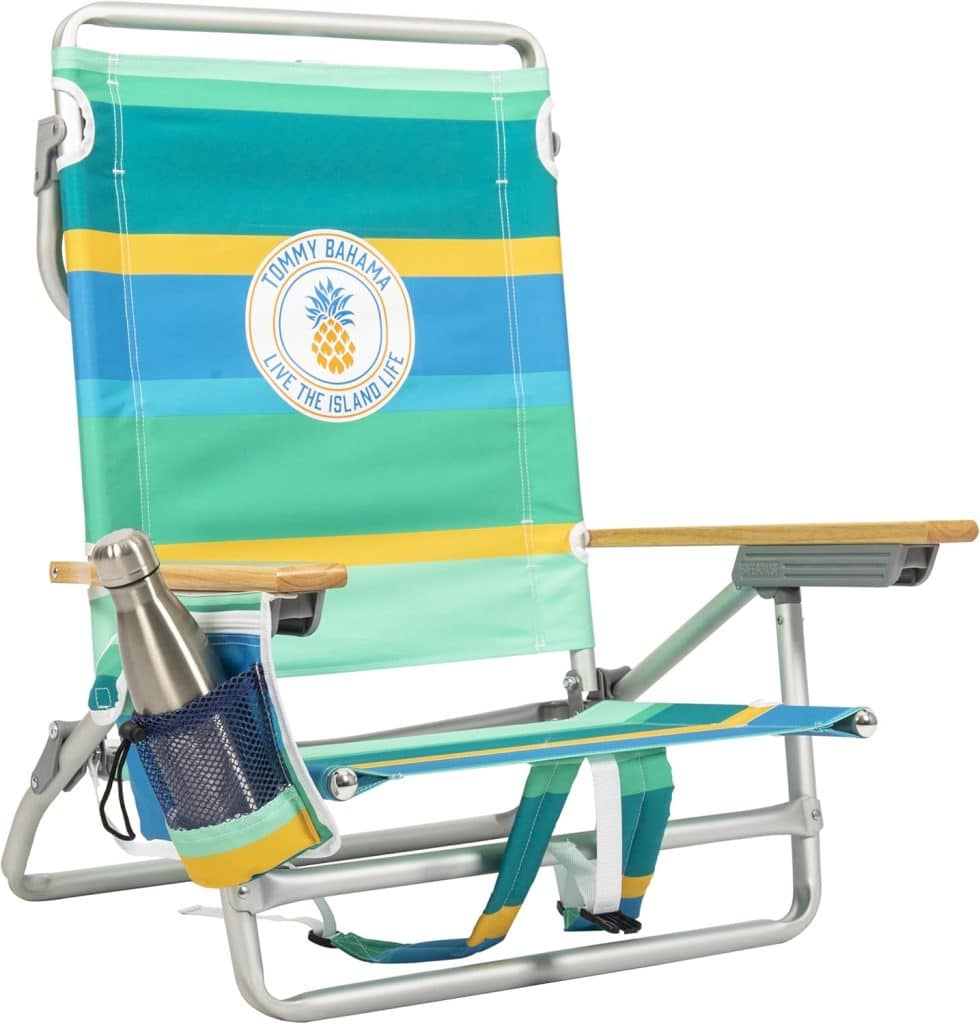 A colorful Tommy Bahama beach chair with blue, green, yellow, and orange stripes pairs perfectly with outdoor tables and chairs. It features wooden armrests, a cup holder with a metal bottle, and the "Tommy Bahama Live the Island Life" pineapple logo.