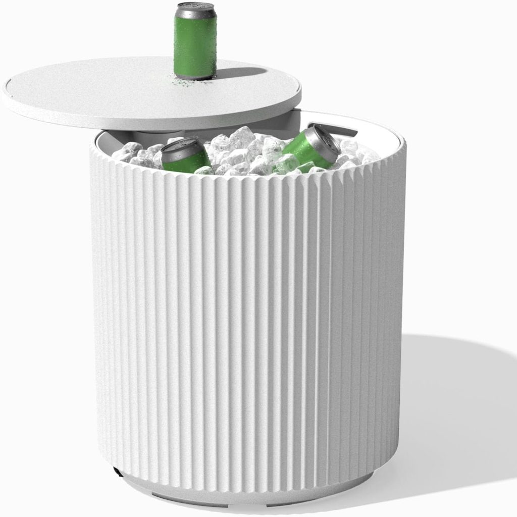 A modern white ribbed cylindrical cooler sits beside outdoor tables and chairs, its lid partially open to reveal ice and three green cans inside. One can rests on the edge of the open lid, ready to refresh.