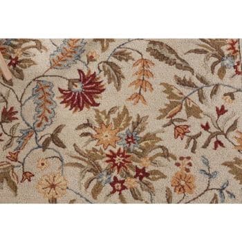 A beige carpet with a floral pattern in shades of red, orange, blue, brown, and green, featuring various leaves and flowers spread across the surface.