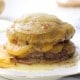 A stack of cheesy, melted French onion soup burgers inspired by the In-N-Out Burger Recipe (Flying Dutchman), topped with caramelized onions and gooey cheese, with savory juices and melty cheese pooling at the bottom.
