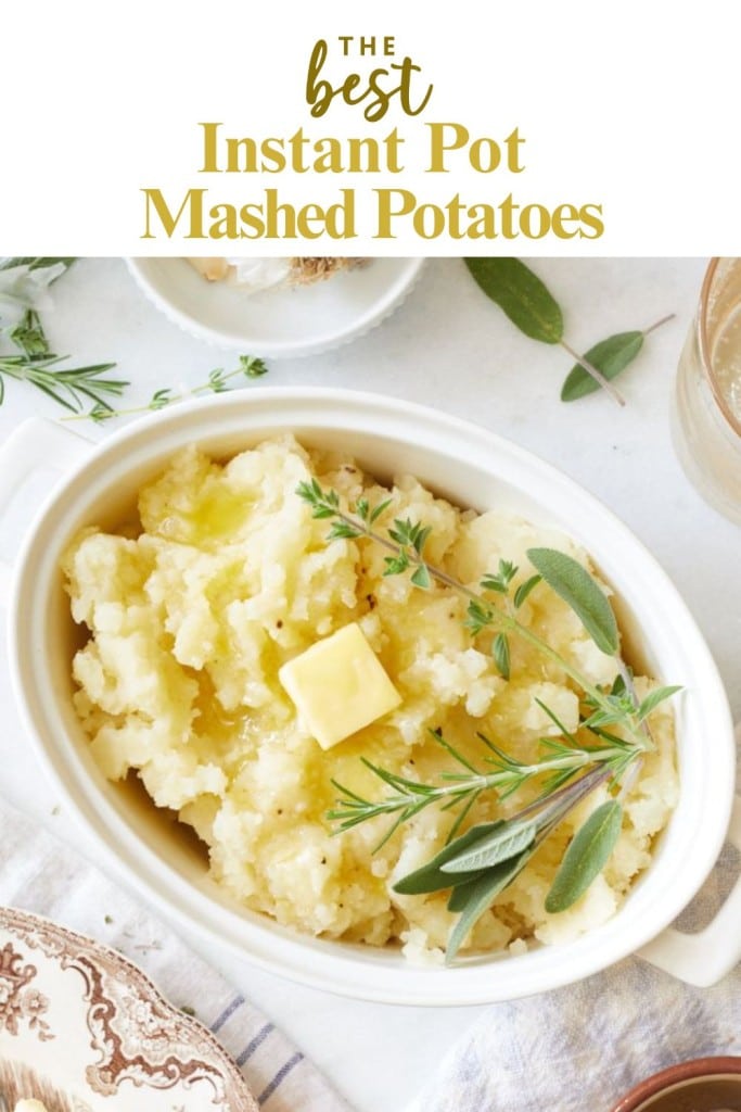 Oval white dish filled with creamy Instant Pot mashed potatoes, topped with a pat of butter and fresh herbs, set on a white surface with extra herbs and a glass nearby. Text reads "The best instant pot mashed potatoes recipe.