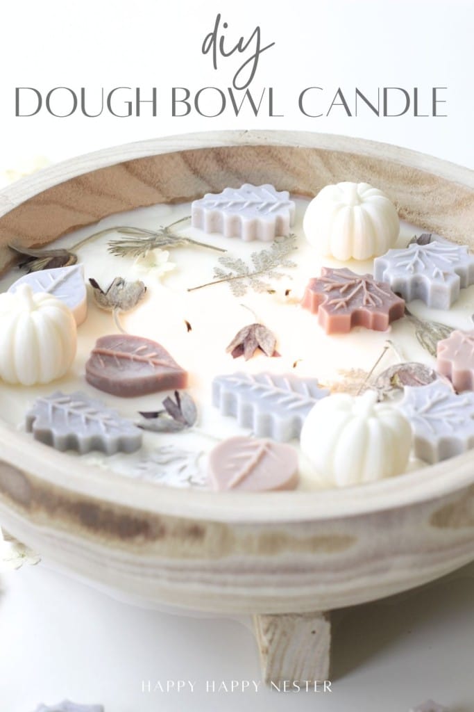 A charming dough bowl candle DIY featuring pastel wax leaves and pumpkin shapes, nestled among dried flowers. The text “DIY Dough Bowl Candle” tops the image, with “Happy Happy Nester” at the bottom.