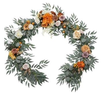 A heart-shaped wreath made of green leaves and decorated with various flowers in shades of orange, white, yellow, and purple.