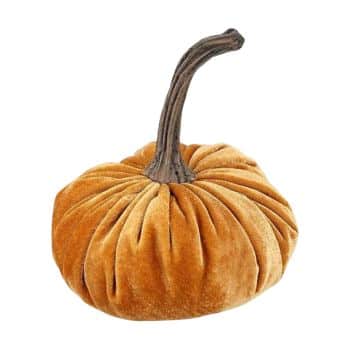 A soft, plush pumpkin made of orange velvet fabric with a long, twisted brown stem, designed as a decorative item.