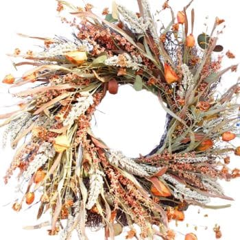 A circular wreath made of dried leaves, orange flowers, and beige sprigs arranged in a rustic, natural style against a white background. The center of the wreath is open and unadorned.
