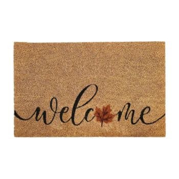 A brown doormat with the word "welcome" written in black cursive letters, featuring a red maple leaf replacing the letter "o".