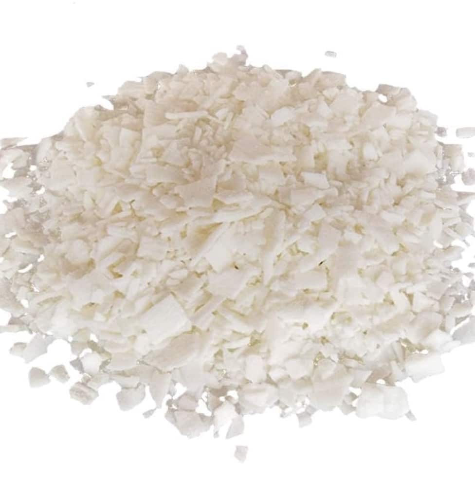 A pile of white, flaky solid pieces scattered on a white surface, resembling soap flakes or wax chips—perfect for your next dough bowl candle DIY project.