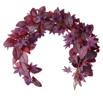 A curved garland made of artificial leaves and flowers in various shades of purple and magenta, arranged in a crescent shape against a white background.