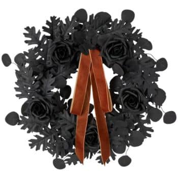 A wreath made of black leaves and roses, decorated with a brown velvet ribbon hanging down the center.