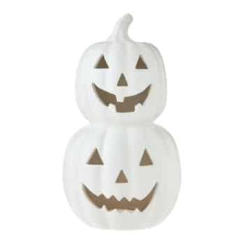 Two white pumpkins are stacked on top of each other, each carved with triangular eyes and noses, and jagged smiling mouths, resembling jack-o'-lanterns.