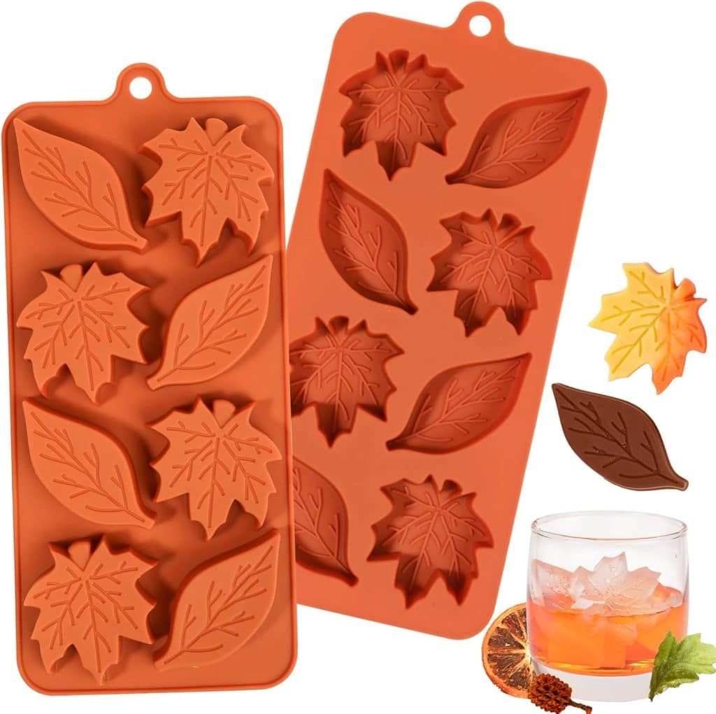 Two orange silicone molds with leaf shapes, perfect for dough bowl candle DIY projects, are shown. Molded leaf-shaped items in yellow, orange, and brown, plus a glass of ice and a dried orange slice, are also visible.