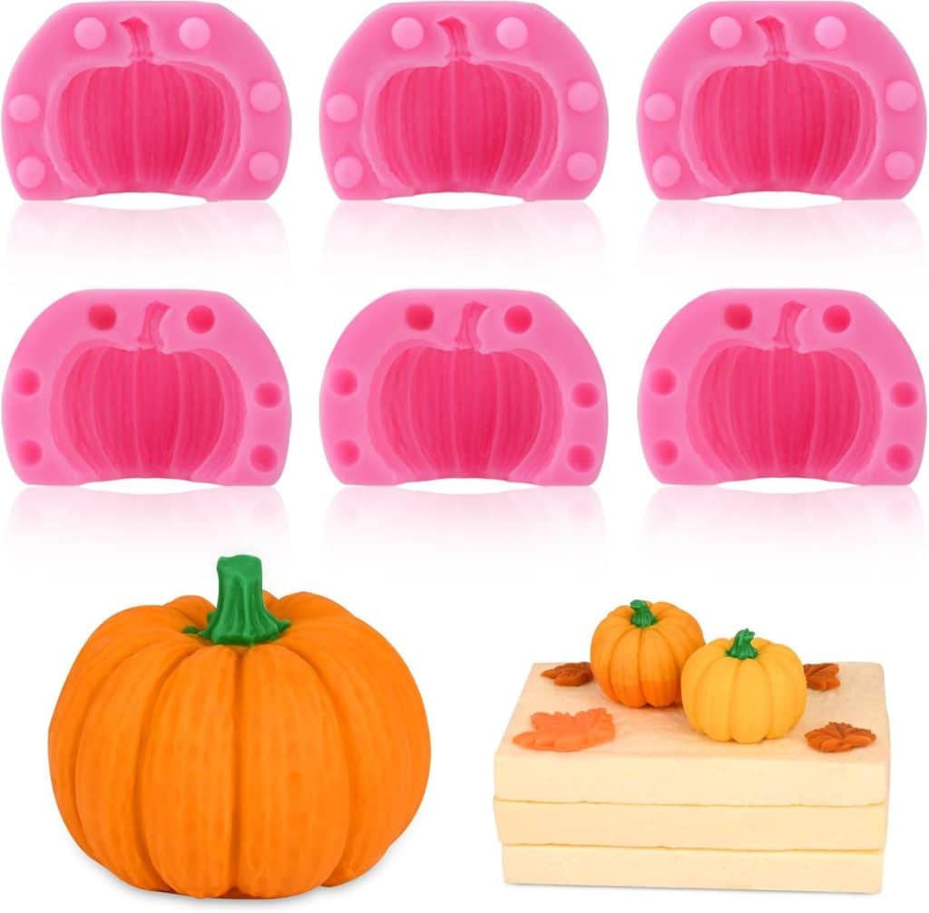 Six pink silicone pumpkin-shaped molds are displayed above realistic-looking pumpkin decorations and a cake topped with two small pumpkins and autumn leaves—perfect for your next dough bowl candle DIY project.