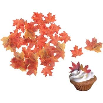 A group of edible autumn leaf-shaped decorations in shades of orange and brown, with one cupcake topped with white frosting and two of the leaf decorations—perfect for festive Thanksgiving treats.