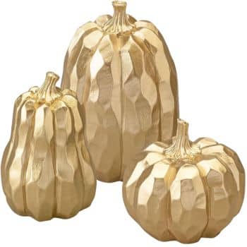 Three faceted decorative pumpkins painted gold, each with a different shape and size, arranged together on a plain background—my favorite Thanksgiving decor for adding festive charm.