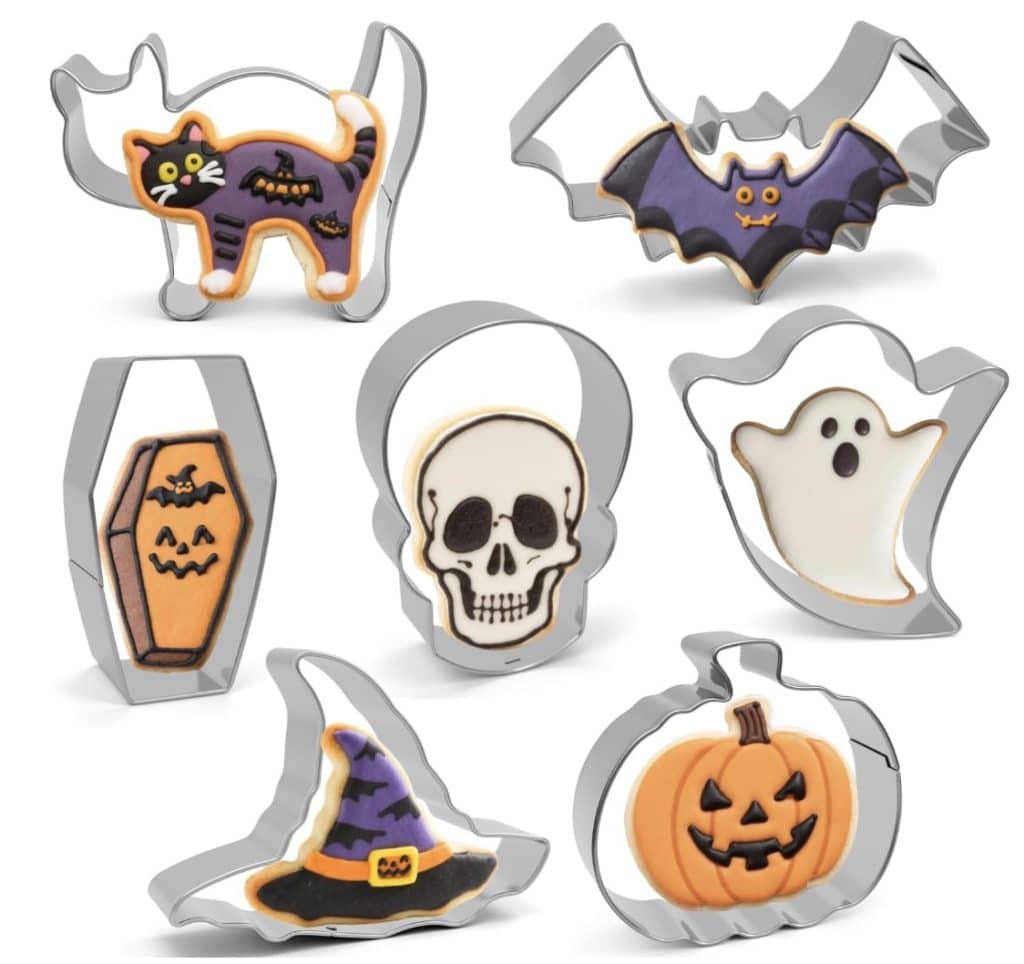 Seven Halloween-themed cookie cutters with matching decorated cookies in the shapes of a black cat, bat, coffin, skull, ghost, witch hat, and pumpkin—perfect for pairing with your favorite Halloween bark recipe—displayed on a white background.
