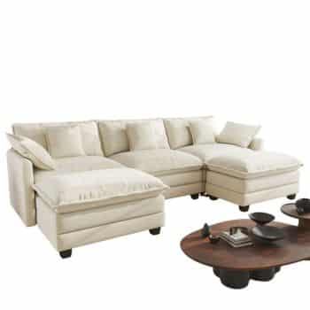 A cream-colored sectional sofa with plush cushions and a chaise lounge, paired with a dark wooden coffee table holding minimalist decor items.