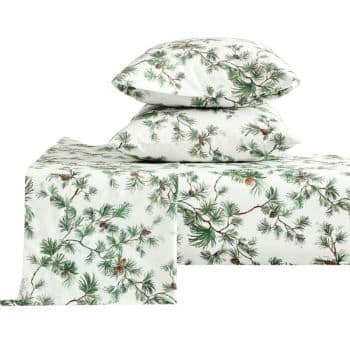 A bedding set with a white background featuring a green pine branch and pinecone pattern. The set includes two pillows and neatly folded sheets, all displaying the same botanical design.