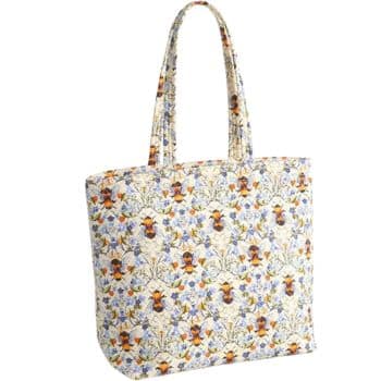 A fabric tote bag with two handles, featuring a colorful floral and bee pattern on a light background.